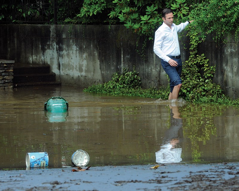 Realtor DJ Denner checks on the condition of one of his listings by wading through standing water in the driveway. photo Mike Wakefield, North Shore News