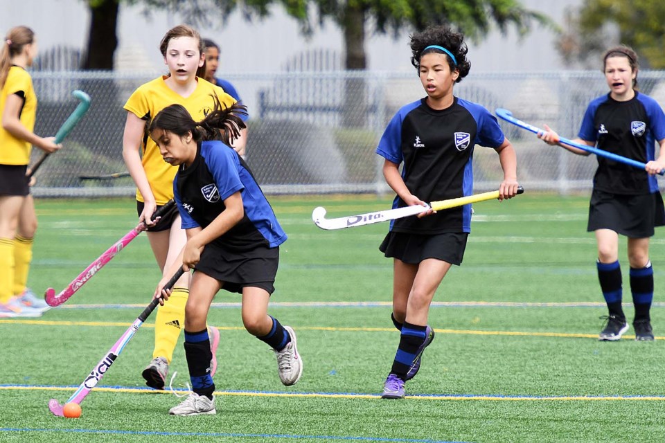 Jenna Khanji, in blue, drives towards the Tri-City net while teammates Mika Melles, centre, and Sarah Gallant provide support in under-13 girls field hockey action.