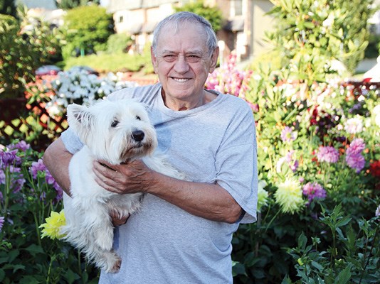 Manie Dutoit with his dog Finlay in his flower garden.
