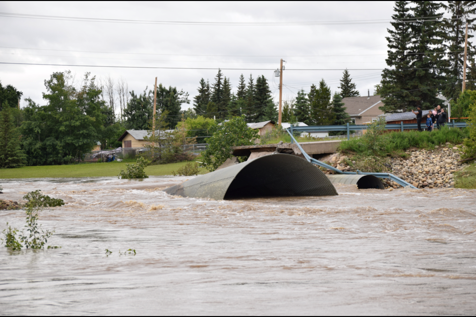 Water rushes through the remains of 15th Street June 17. The city aims to replace the crossing, which burst after its culverts became plugged, with a bridge by the fall.
