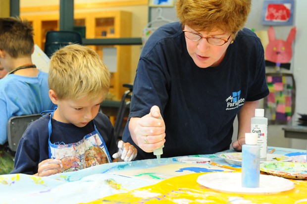 Parkgate Community Centre's art instructor Maureen Coles helps 6-year-old Dylan MacAulay with his Sandy Hands art project during a summer camp held the week of July 25th.