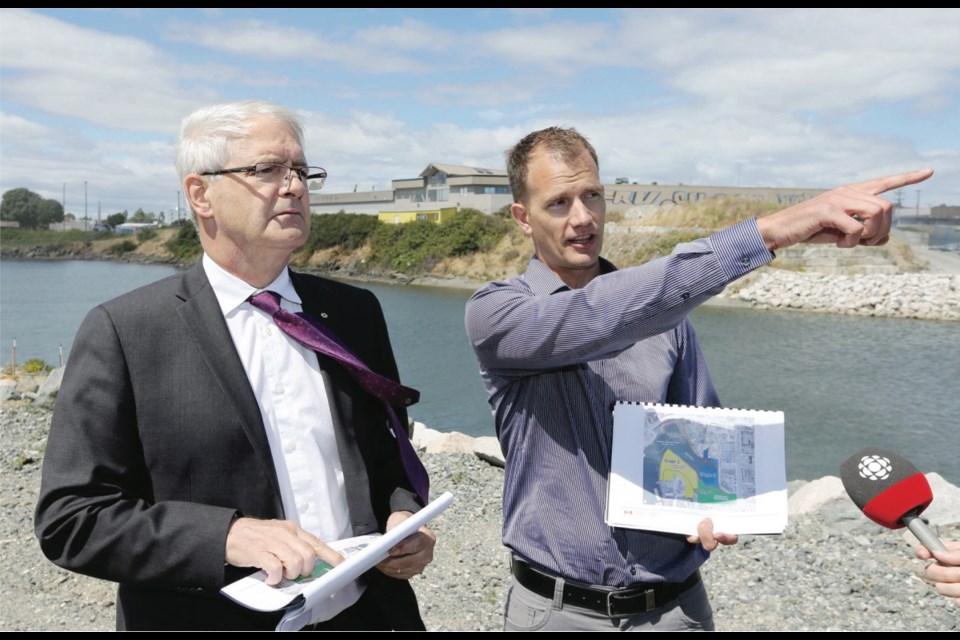 Federal Minister of Transport Marc Garneau, left, and Ian Chatwell, regional manager of environmental services for Transport Canada, review the areas in and around Rock Bay that have been remediated.