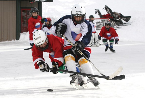 Above and right: Thomas Harris of the Hollyburn Huskies (in red) makes a diving play for the puck during a Feb. 26 outdoor minor hockey tournament on Grouse Mountain.