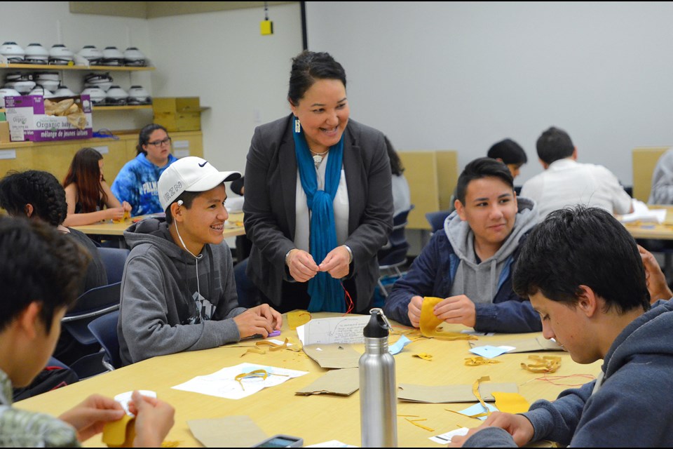 Marcia Guno, director of SFU's Indigenous Student Centre helps a group of high school students at the university's Academic Summer Camp for Aboriginal Students make medicine bags.