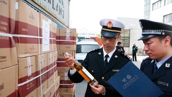 Chinese customs officials are seen inspecting and documenting seized boxes of Lulu Island WInery wine. Photo sourced from XinMin.com