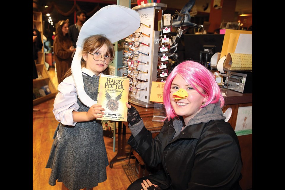 Cordelia Kinch, 7, left, receives the first copy of Harry Potter and the Cursed Child from Kayli VanderMeer, Books & Company manager, right, on Saturday. Kinch won the Harry Potter costume contest with her Moaning Myrtle costume and her prize was the first copy of the book off the shelves, free of charge, at the stroke of midnight when the book was officially released. Citizen Photo by James Doyle July 30, 2016