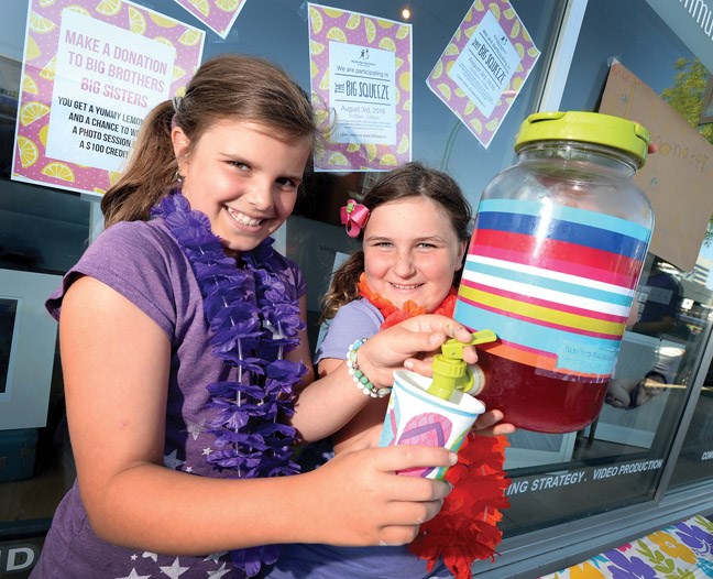 When life hands you lemons-Sofia Carpino, 9, and Cora Reimer, 8, pour lemonade, all natural hibiscus honey berry infused lemonade, at Bobbi Carpino Photoraphy on 4th Avenue one of 18 local businesses and groups participating in Big Brothers Big Sisters Big Squeeze fund raiser Wednesday. Teams battled it out for one of two trophies, one for the best tasting lemonade as deemed by a panel of judges, and the second for the team who raises the most money. All proceeds from the Big Squeeze stay in Prince George to support the agency's proactive mentoring programs.