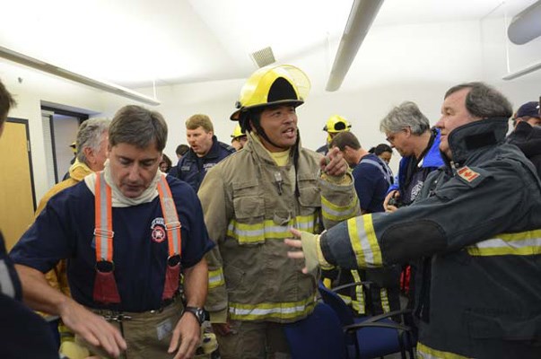 Grant McRadu (left), West Vancouver chief administrative officer, Burnaby Now reporter Alfie Lau and a roomful of delegates to the Sept. 26 Union of British Columbia Municipalities convention suit up in full turnout gear before a day of hot, wet and sweaty firefighter training.