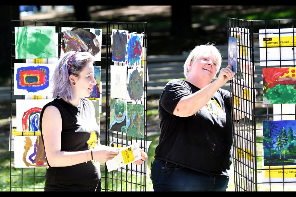 Heidi Benefiel, Opus store manager, hangs art at the paint-out event in Queen's Park.