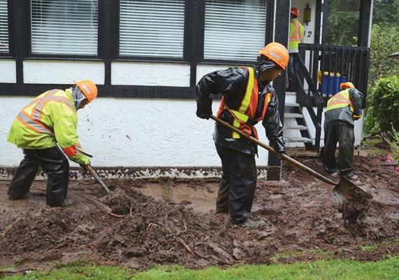 Workers shovel the mud away from the front of this house.