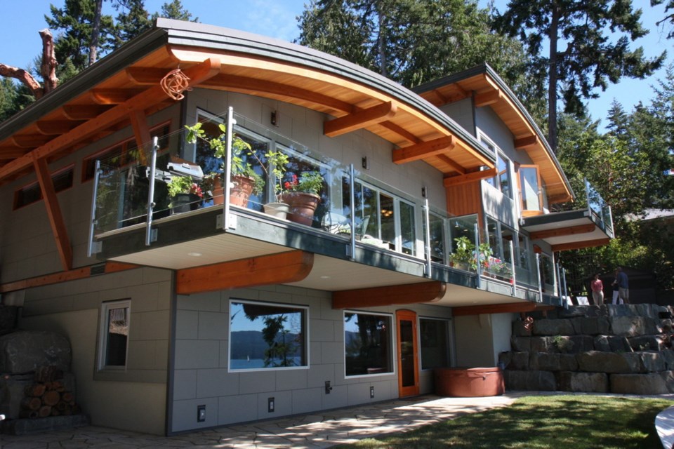 The waterfront home of Fernando and Tami dos Santos was built on a small waterfront lot, and the owners softened its mass by curving the roofline.