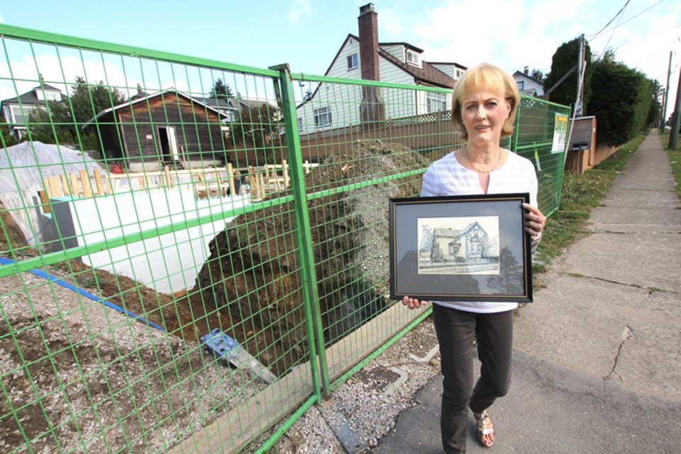 Julie Simmonds stands with a pen and ink drawing of her grandparents’ home at 1031 Sixth Ave. The house was never designated a heritage home and was demolished earlier this summer.