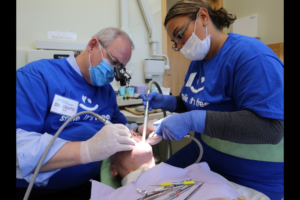 Dr. C. Ross Crapo and assistant Rebeca Flores perform free dental work at a previous Dentistry From the Heart event.