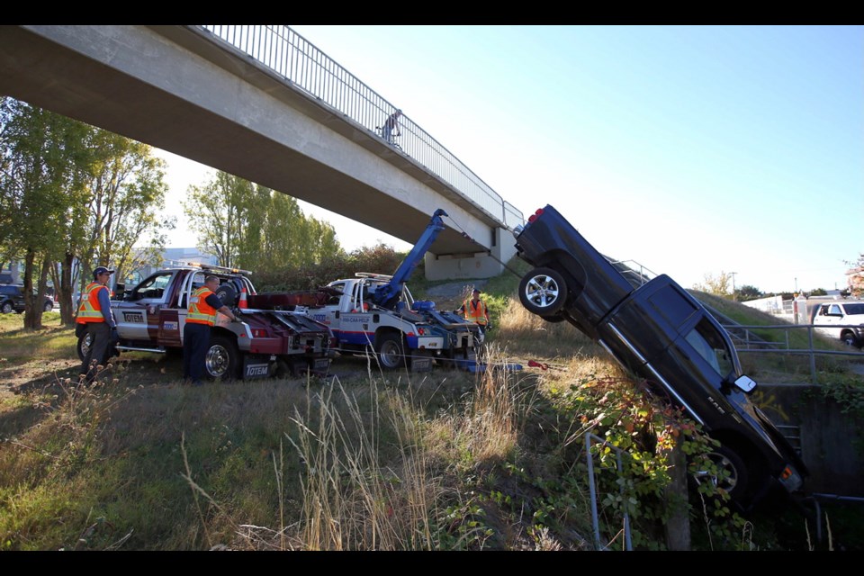 Tow-truck crews remove pickup that crashed into a ditch near Uptown shopping centre on Thursday.