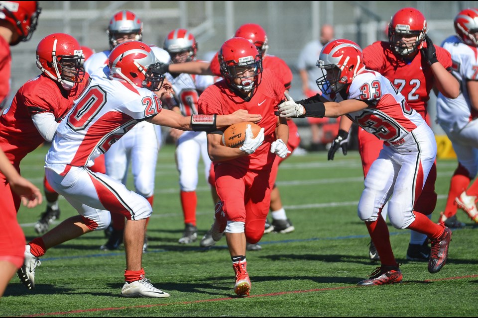 St. Thomas More Knights’ Julian Valerio, centre, rushes the ball Wednesday against the visiting John Barsby Bulldogs in a junior varsity football game at Burnaby Lake West. The Knights took advantage of Barsby turnovers to pick up a 35-16 win.