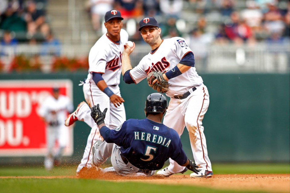 With the a toss from Minnesota Twins shortstop Jorge Polanco, left, second baseman Brian Dozier forces out Seattle Mariners' Guillermo Heredia and turns a double play in the seventh inning of a Sunday's game in Minneapolis. The Mariners won 4-3.