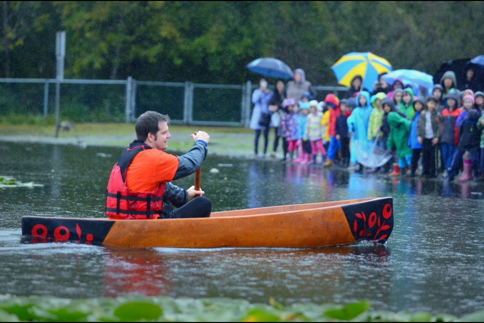 Gilpin Elementary School principal Blake Briscoe is greeted by students from his school as he paddles a traditional First Nations canoe ashore at Deer Lake Friday. Called a skumay, the vessel, traditionally used by coastal women, was built during a three-month artist-in-residence project at Gilpin by Squamish First Nation artist Aaron Nelson-Moody.