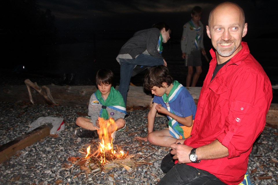 Cub leader Geoff Degner enjoys a bonfire with Cubs Max and Colin.