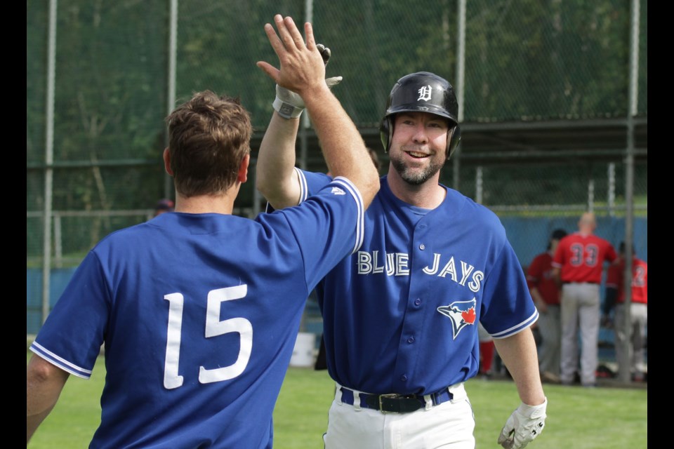 Burnaby’s Reid Wildeman, right, is congratulated by a teammate after launching a two-run home run, helping to power the Blue Jays past the Howe Sound Hounds in the B.C. Over-30 Baseball League championship game last week at Robert Burnaby Park.