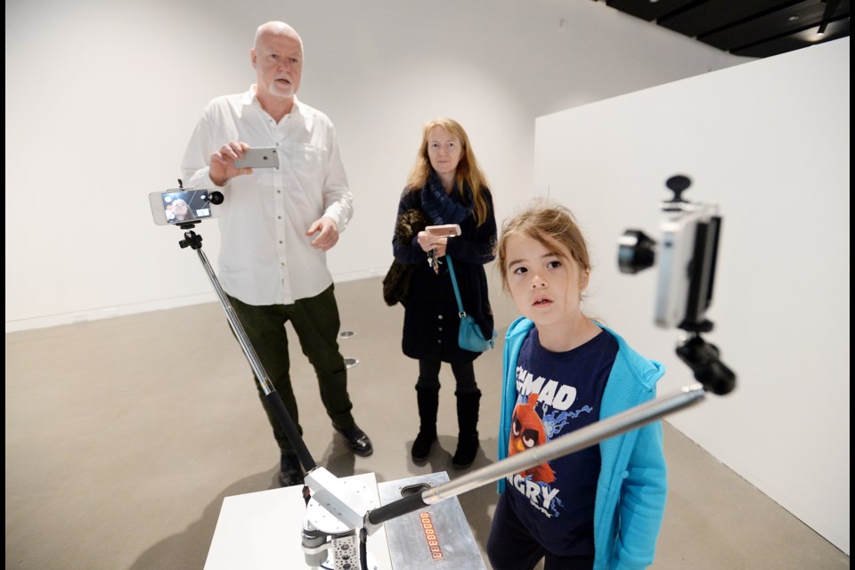 Dean Self gets up close and personal with one of the installations at the WITNESS exhibition at New Media Gallery, as director-curator Gordon Duggan and mom Janet Self look on.
