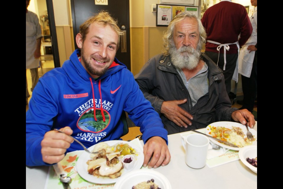 Family members Matthew Cummins, left, and Ken Chalkley eat lunch at the annual Thanksgiving event at Our Place.