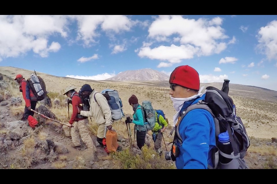 Bill Der, second from left, treks up a path with help from his team during a summit attempt on Tanzania's Mount Kilimanjaro last month. His son Spencer, in blue in the foreground, eventually went on to the summit alone after his father, who is legally blind, had to call off his climb because of altitude sickness.