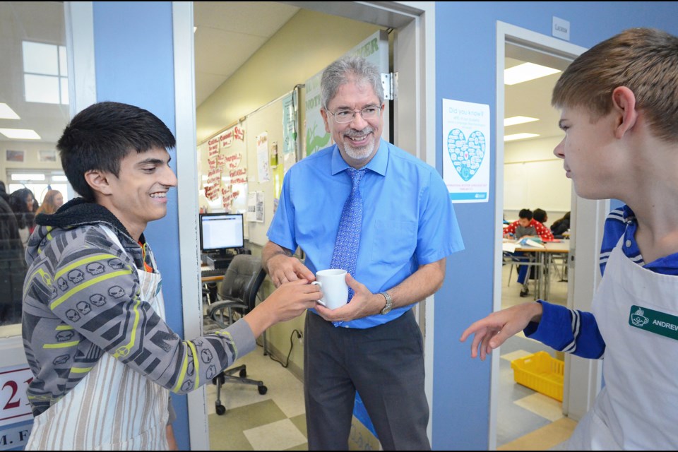 Byrne Creek Secondary students Ricky Parmar, left, and Andrew Trebunski, right, deliver a coffee to French teacher Maurice Fouquette as part of the school's coffee program.