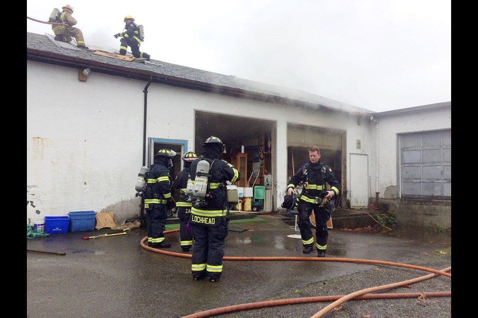 Firefighters open up the roof of Qualicum Beach's Remember That Collectibles on Fern Road after fire broke out Friday morning at about 10:30 a.m. The blaze, which killed one man, was contained.