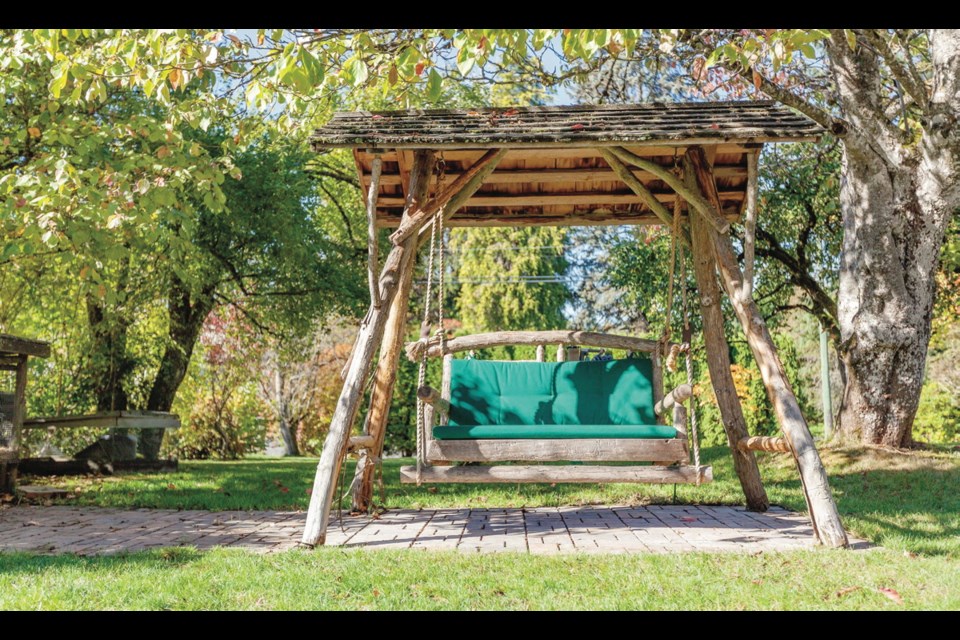 An A-frame, shake-roofed swing looks romantic in the garden. John Lore has made 100 of these, all from salvaged cedar limbs.