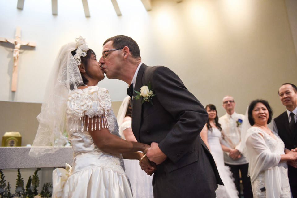 Joseph Heck kissed his bride Sherly during a mass wedding at St. Mary’s Parish where 15 couples were married at the same time. Photograph by: Rebecca Blissett