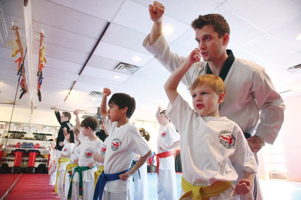 Instructor Chris Izdebski helps Blake Dunbar with his pose at a Taekwondo Camp at North Shore Taekwondo.