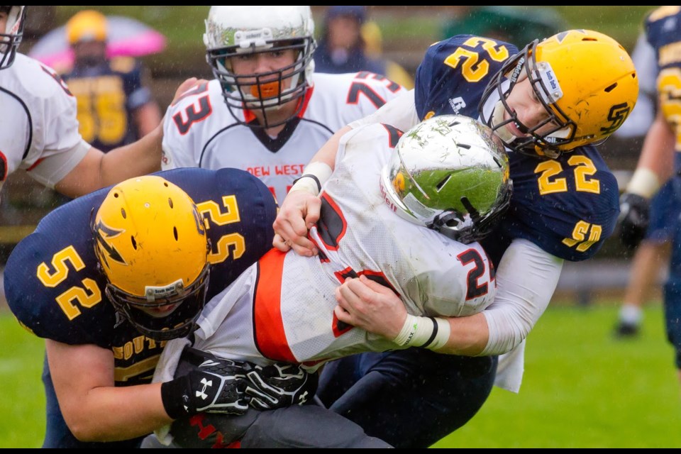 New Westminster Hyacks’ Trew Dancey, centre, puts a grip on South Delta’s Grant McDonald, while Greydon Welch, at left, returns the favour during Saturday’s AAA high school football game in Delta. The Hyacks fell 42-14 in the annual Bill Kuschner Cup game, which also signalled the end of the regular season.