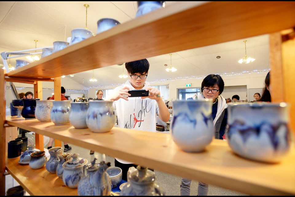 Ryan Moon takes a picture of high-fire porcelain by Gloria Stephens at the Burnaby Potters' Guild winter show and sale at the Capitol Hill Community Hall.