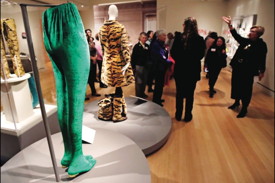 In this Tuesday, Nov. 15, 2016 photo, an Anne Klein green stocking boot, from the 1980's, is displayed as curator Lynda Roscoe Hartigan, right, gestures during a tour of the gallery at the Peabody Essex Museum in Salem, Mass. From flats to stilettos, what we put on our feet says something about who we are. That