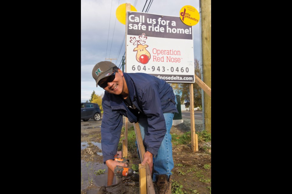 Volunteer Gord Chan erects an Operation Red Nose sign on Arthur Drive as the safe driving program is underway for another holiday season.