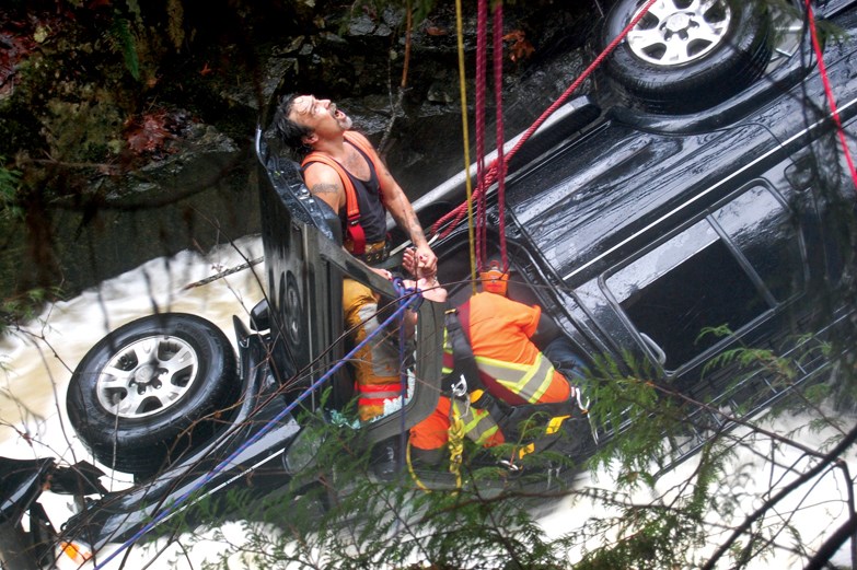 Firefighters Bill Gilkes (left) and Tyrel Brackett perform a high angle rescue to free a Surrey woman trapped after her SUV plunged into a creek near Middlepoint on Nov. 23.