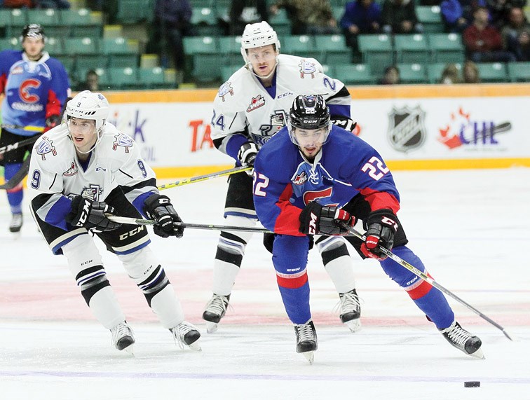 Cougars winger Yan Khomenko looks down at the puck while leading a rush into the Victoria zone while being chased by Royals forwards Jack Walker (9)and Regan Nagy (24) during Saturday's game at CN Centre.