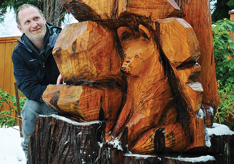 Lumberjack and chainsaw artist Nick Hall spies the hidden fox in a bear sculpture he carved for a North Vancouver family as a way to honour a beloved tree. photo Cindy Goodman, North Shore News