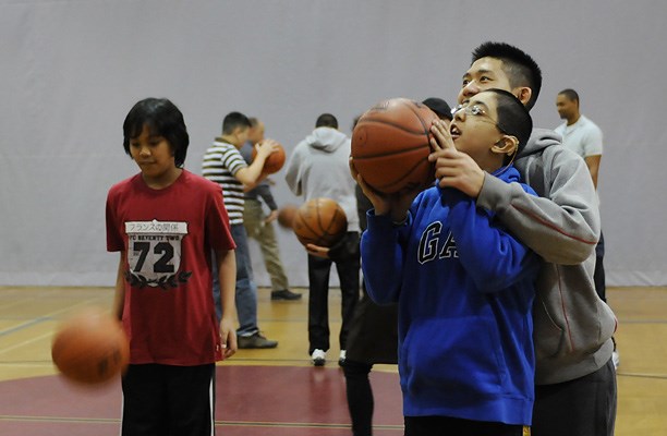 St. George's student Andy Lu coaches Windermere's Aneesh Bangar to shoot a basket while Jared Astudillo bounces a ball.