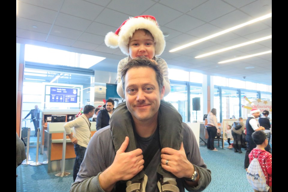 Jackson Russell sits on dad Jesse’s shoulders prior to boarding an Air Transat flight organized to find Santa. The flight is a joint initiative between the Children’s Wish Foundation and Air Transat. Photo Sandra Thomas