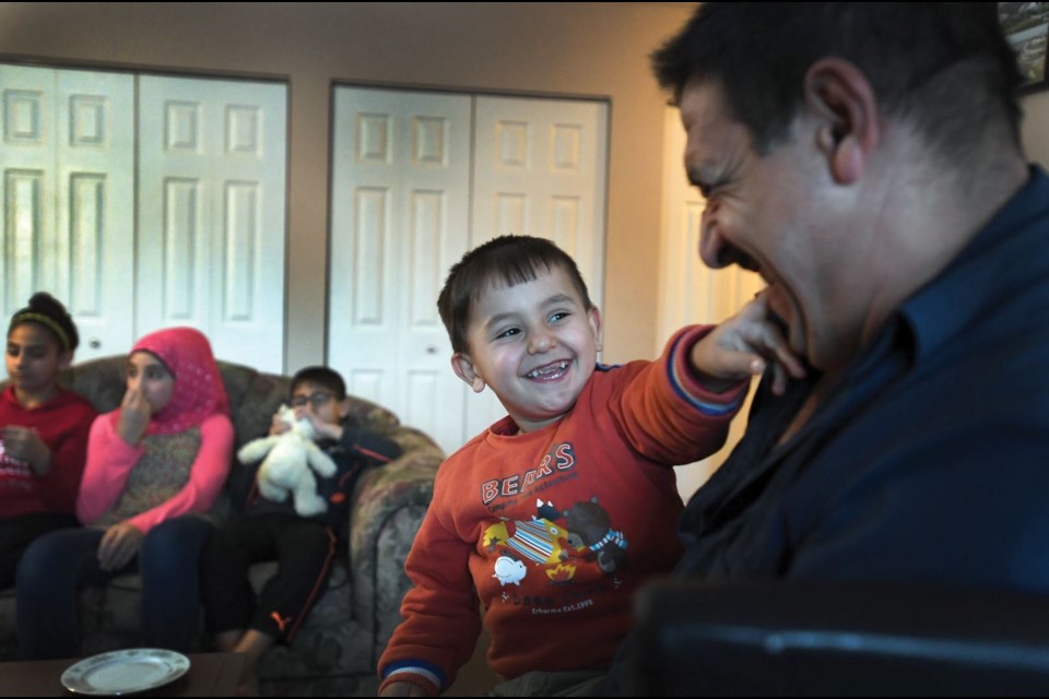 Mostafa Khalaf enjoys a moment with his two year old son Mohamad in their apartment on Dec. 19. Khalaf and his family arrived in Canada in February.
