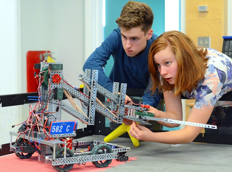 A pair of Alpha Secondary robotics students prepare their machine for a scrimmage.
