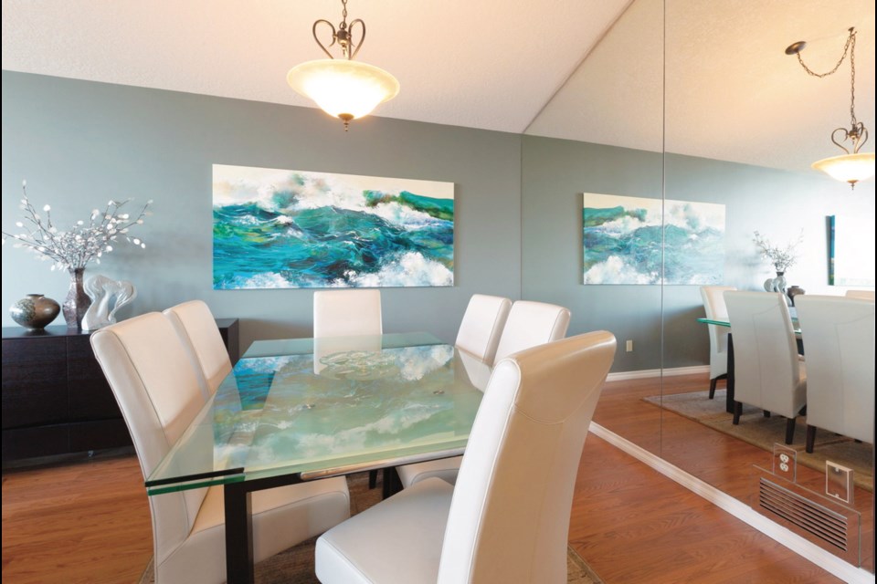 A mirrored wall at right appears to double the dining room, while a glass-topped table reflects an image of Kathryn Amisson&rsquo;s waterscape.