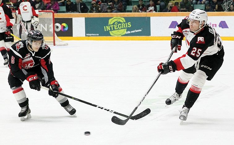 Prince George Cougars defenceman Tate Olson, right, plays the puck past the outstretched stick of Justin Almeida of the Moose Jaw Warriors on Friday at CN Centre.