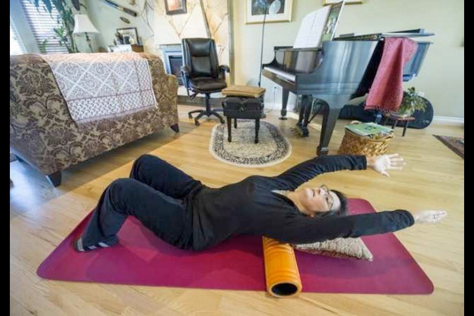 Dr. Rassamee Ling stretches, using an exercise roller, as part of her post-operative rehabilitation from breast cancer.