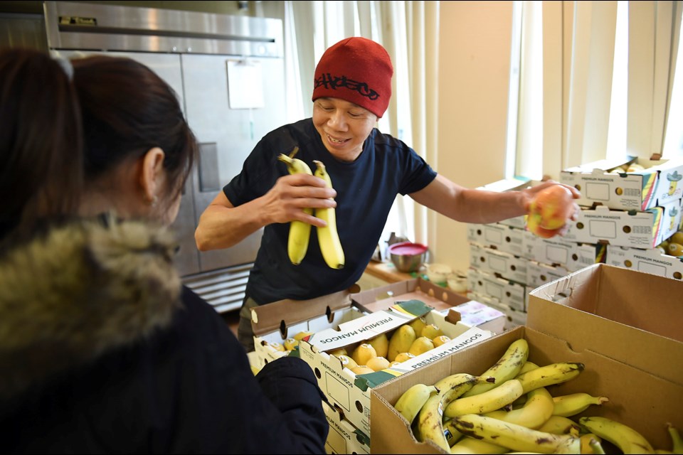 A volunteer hands out fresh fruit at Strathcona Community Centre Jan. 27, 2017. The free weekly food program is at risk if the community centre can't secure funding for the program's co-ordinator. Photo Dan Toulgoet