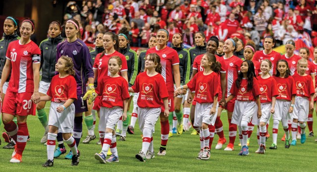 Players from the North Shore Girls Soccer Club accompany the starters for Team Canada’s matchup against Mexico onto the pitch for an exhibition game Saturday at BC Place. Lucky players from the club also got to watch Christine Sinclair and the rest of the national team practise at the North Shore Bubble on Sunday. photo Stewart Johnson