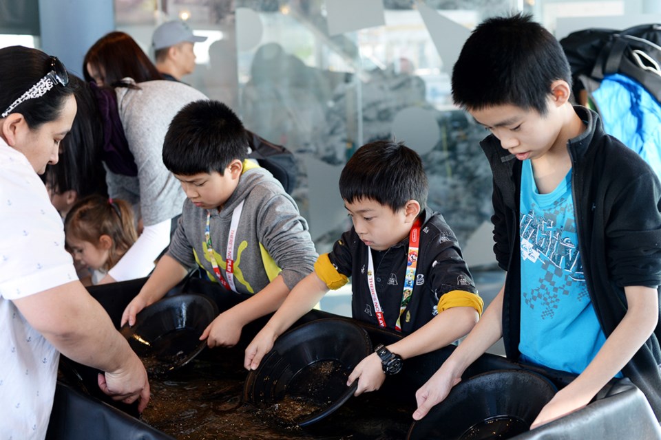 Louise Bertok demonstrates how to pan for gold at the Fraser River Discovery Centre. Ethan (left) and Brandon Fong, and Nathan Chow (right).
