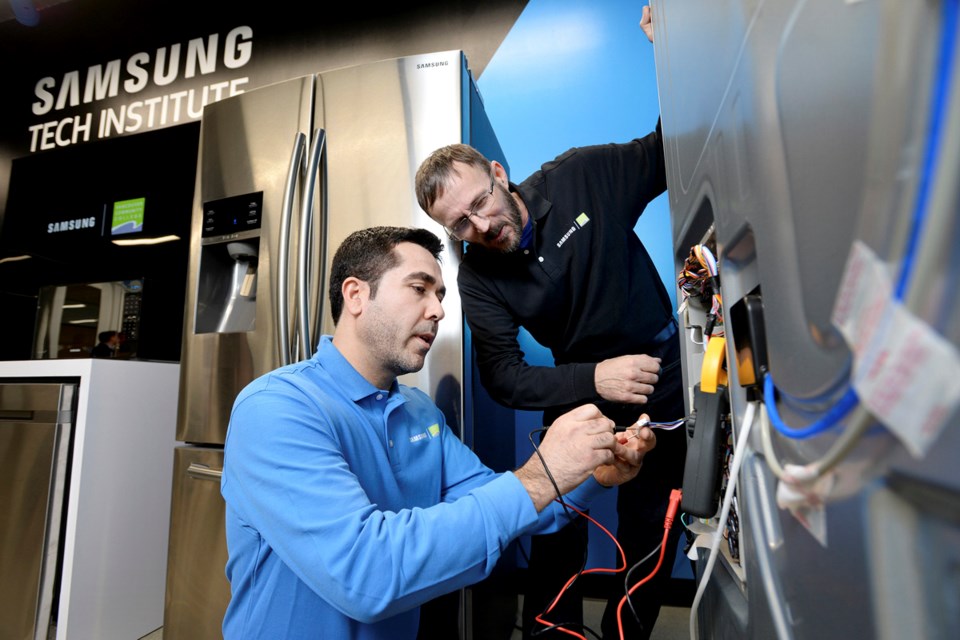 Vancouver Community College student Reza Golshane and Samsung Tech Institute instructor Noel Vanderveer work on a fridge at the institute's unveiling Feb. 23. Photo Jennifer Gauthier