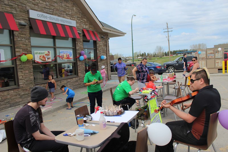 Team member Kevin McKay serenades families gathered outside the Thompson Tim Hortons for Camp Day.